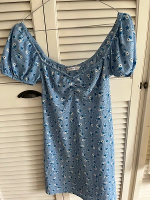 Stradivarius blå blommig klänning - Jättefin sommarklänning från stradivarius i storlek S! Köpt sommaren 2021 men endast använd ca 5 gånger och är i nyskick! Sälja då den inte längre kommer till användning! 