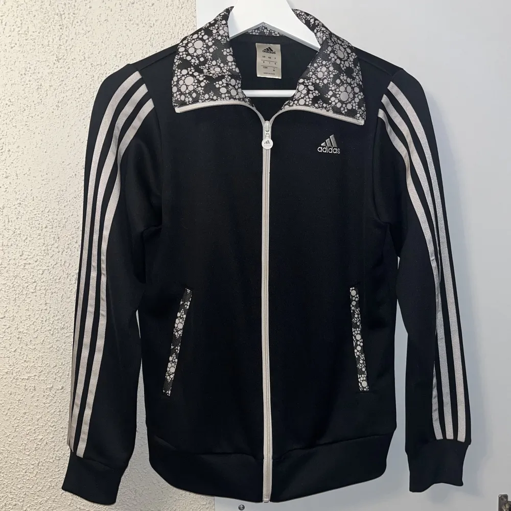 Snygg adidas kofta med lite mönster på!🖤🤍 Finns dragkedjor vid fickorna så att de går att stänga ordentligt 🌸 Säljer då jag inte kan minnas att jag nånsin använt den, men den är iaf i nyskick! Står ingen storlek på insidan men skulle gissa på strl S ❣️. Tröjor & Koftor.