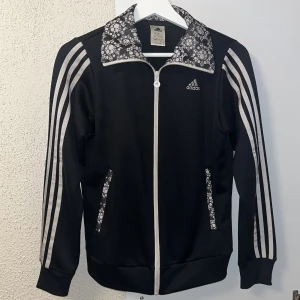 Adidas kofta - Snygg adidas kofta med lite mönster på!🖤🤍 Finns dragkedjor vid fickorna så att de går att stänga ordentligt 🌸 Säljer då jag inte kan minnas att jag nånsin använt den, men den är iaf i nyskick! Står ingen storlek på insidan men skulle gissa på strl S ❣️