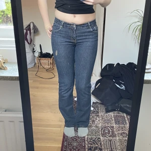 Lågmidjade jeans - Lågmidjade mörka jeans från märket cue. Ganska raka i benen. Insydda i midjan (syns på sista bilden) samt uppsydda. 36cm rakt över midjan. Innerbenslängd 77cm. Finns fler bilder om det önskas:)
