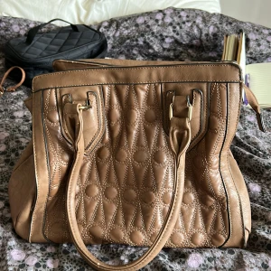 Brun väska - Brun väska köpt på second hand för ett par år sedan. Den har några slitningar utanpå, men väldigt fin annars. Flera fickor i väskan. Ungefär 30x30cm och ungefär 20cm bred 🤗
