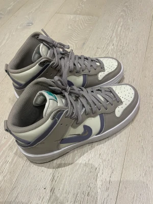 Nike Dunk High Up grå lila - Super snygga Nike Dunk High Up köpta på my Theresa. Tyvärr är de för stora. Som nya endast använda tre gånger. Säljer med original box. Storlek 39 cm 25