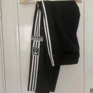 ADIDAS trackpants - Helt nya, klassiska svarta adidas trackpants. Knappar längs sidorna, oanvända! 