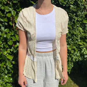 Tunn cardigan - En beige cardigan med vita detaljer, tunt och luftigt material, perfekt att klä upp och till vardags.