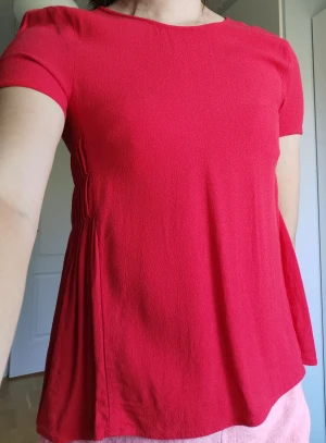 Röd t-shirt med snygga detaljer i sidan - Superfin röd t-shirt med jättefina detaljer i sidan. Passar utmärkt inför sommaren ☀️ Toppskick!  Material: 100% viskos 