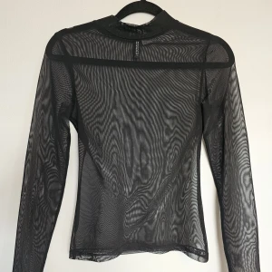 Svart mesh-topp - OBS tröjan har inget mönster, det bara blir så i kameran! Plain svart mesh, storlek XS men passar även lite större. Använd endast en gång, mycket gott skick. Tvättas självklart innan utskick/överlämning! 
