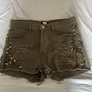 Shorts med Guldiga Nitar - Slitna militärgröna shorts med guldiga nitar. Använt men bra skick.