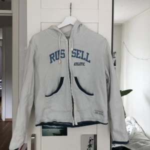 Vit hoodie  - Vit hoodie från Russell atletic med knapp stängning, köpt secondhand  men jag har aldrig använt den  Köpt för 160kr Säljer för 70kr