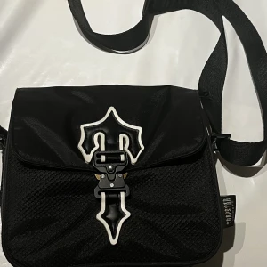 Trapstar axelväska - Äkta Trapstar bag, Har haft denna i ett och halvt år inte använt mycket allts. Delen på vänstra t:et som är lite konstig, så fick jag den