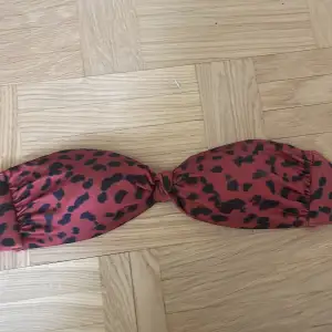 Röd bandaue bikini med rött leopard mönster. Säljer pga att den var för liten. Passar jättebra till en svart underdel eller en vinröd. 