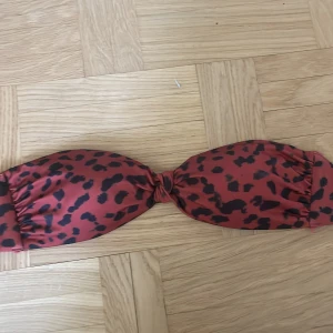 Leopard bikini - Röd bandaue bikini med rött leopard mönster. Säljer pga att den var för liten. Passar jättebra till en svart underdel eller en vinröd. 