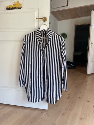 Svartvit skjorta  - Svartvit randig skjorta i två olika material, ärmarna är ett tröjmaterial medan resten av skjortan är glansig 