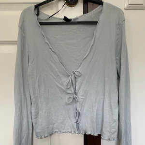 Ljusblå kofta - Söt långärmad kofta med någon detalj längst ner på tröjan och ärmarna, två knytningar i fram för att stänga <3 typ oanvänd