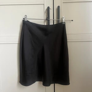 Svart silkeskjol - Svart kort kjol i silke med dragkedja vid sida. Från NA-KD 