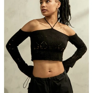 Stickad offshoulder topp - Såå snygg slutsåld svart virkad topp med coolt mönster och snöre som man knyter runt nacken. Köptes från Urban outfitters för ca 600kr. Den är knappt använd! 