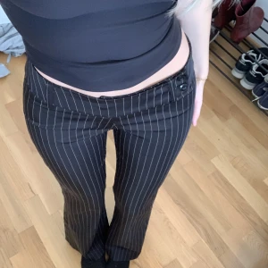 Lågmidjade kostymbyxor  - Mina älsklingsbyxor. Perfekt passform, lågmidjade med snygga knappar och utsvängda ben. Midjemåttet är 35cm sen har de lite stretch också. Innerbenslängd är 78cm men sen har de en fåll på 4,5cm som man kan ta ner