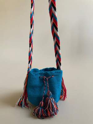 This mini bucket bag is constructed in Colombia with colorful threads made of Cotton and Aloe. The braided shoulder strap can be easily adjusted by tying a knot to shorten. Drawstring Closure with Fringed Pom Poms.  #drawstring #vintage #bucketbag 