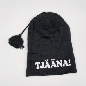 Mössa med tofs TJÄÄNA! roligt tryck moderiktigt motiv - Mössa med tofs och det rätta "hänget"  (tofsen kan klippas bort) One size fits all  100% akryl Helt oanvänd på alla sätt 