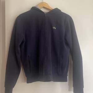 En väldigt snygg mörkblå hoodie från Lacoste, står att den är storlek 176 men skulle säga den sitter som S, köpare står för frakten