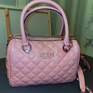 Superfin rosa väska från Guess, den är helt ny, endast använt den en gång, sedan dess har den bara legat i garderoben. c.30 cm i bredden, kan skicka fler bilder ifall det önskas !! 