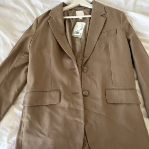 Blazer H&M - Oanvänd beige/brun oversized blazer från H&M i storlek XS. 