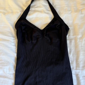 Svart halterneck - Svart halternecklinne från ”reflex” i storlek M. Väldigt stretchigt material och band knyts i nacken.