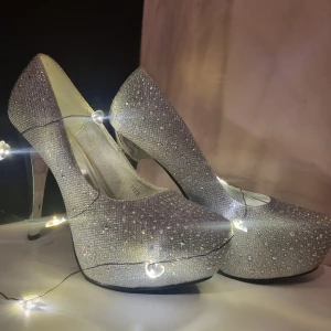 Glittrande silverpumps med skimmrande stenar  - Dessa klackar är oanvända. De är enbart provade och vackra till allt så som utekvällar till dragqueen upvisningar!  Även om skorna är helt nya så syns tyvärr drt gulande limmet på t.ex sulan unnuti skor o klacken har några små osynliga repor. 