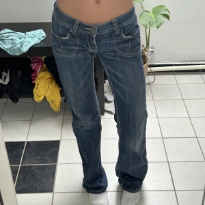 Lågmidjade bootcut jeans - Säljer nu mina så snygga lågmidjade jeans! De är mörkblå och bootcut med detaljerade sömmar och coola fickor. De är från BSM och i storlek 26🩷Defekter finns nere vid fötterna då de var långa på mig som är 168, skicka pm för bild, annars super skick!💗
