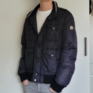 Moncler jacka - Extremt fet moncler vinterjacka! Superfint skick, inga hål eller skador! Storlek 5, passar mig som är 185, 65kg. Äkthetsbevis finns! Hör av dig vid minsta lilla fråga🙂