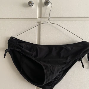 Oanvänd bikiniunderdel storlek 42 - Oanvänd bikiniunderdel, täckande bak med dragsko-dekoration i sidorna. Storlek 42, aldrig använd då storleken inte passade 