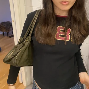 Vintage Militärgrön axelväska - Väskan är i bra skick, inga synliga tecken på användning. Har en mocka sida och glansiga kortsidor samt straps! 🖤 Medium stor väska. Y2k 2000s stil.