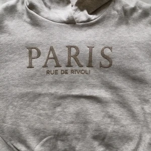 Paris Hoodie med glitter - En Hoodie utan stören med text på franska i guldaktigt glitter.  Aldrig använd 