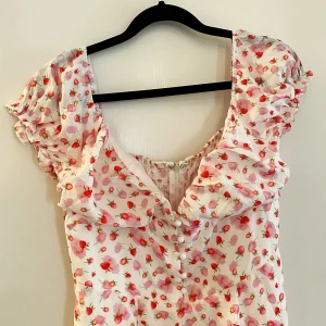 Sommarklänning s - En fin klänning med liten slits och knäppning i bysten  Somrig med jordgubbsmönster