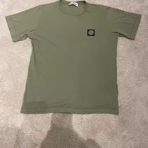  Säljer denna mörkgröna Stone Island t-shirt i bra skick ett pytte litet hål som knappt syns tröjan Är i storlek tolv år / 156 cm nypris 800 till 1000 skriv vid intresse!