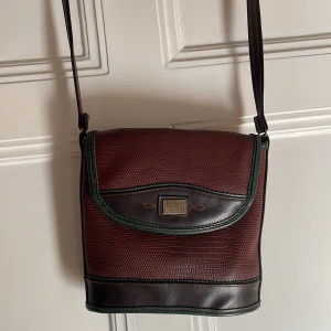 Retro handväska från Duffy - Retro handväska från märker Duffy. Väldigt fint skick utvändigt. Invändigt finns ett hål i innertyget (se sista bild), inget som dock inte den händige kan fixa! En innerficka samt bakficka finns.