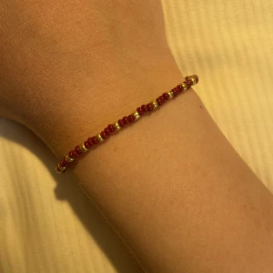 Armband - Superfint handgjort armband med vinröda och guldiga pärlor. Armbandet har även en karbinhake och en förlängningskedja på så det går att stänga. Skickar med postnords frakt 15kr. 