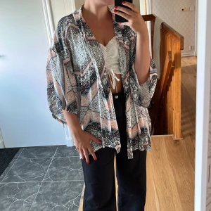 Kort kimono - Färgglad, mönstrad Kimono med breda och luftiga ärmar. Inköpt för många år sedan, och knappt använd sen dess.  Rosa, marinblå, svart och vit. Står storlek XS/S, men min mor lånade den för ett tag sedan och hon är storlek L. Funkade fint.