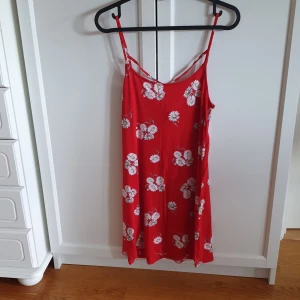 Klänning  - Kort klänning eller långt linne. Det är upp till var och en. Vita prästkragar på röd botten. Divided/ H&M. Kryss i ryggen. 