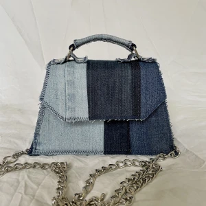 Jeans handväska - Liten handväska gjord av gamla jeans. Sydd av mig. För mer jeans återbruk www.SbyIsabelle.com  Mått på väskan är Bredd: botten 21 cm, top 15 cm Djup: botten 8 cm, top 6 cm Höjd: 13 cm Magnet knapp i locket för stängning. 
