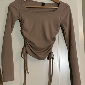 Långärmad tröja - Säljer min långärmade tröja med snören ner till. Snygg och brukar passa till vardags. Fint skick, använd någon gång. 