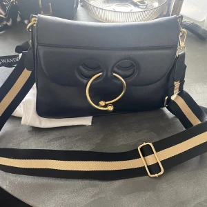 JW Anderson väska - Supersnygg JW Anderson Pierce väska. Jättefint skick, dock utan originalaxelrem då den är borttappad. Men minst lika snygg med den axelremmen som är på nu! 