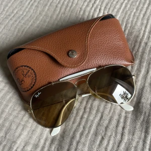 Ray-Ban solglasögon pilot  - Äkta Ray-Ban solglasögon i pilotmodell. Guldig båge med brunt glas och visa detaljer. Använda men i fint skick.