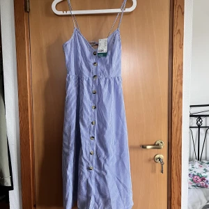 Randig klänning - En randig klänning med knappar som går till mitten på smalbenet ungefär. Helt oanvänd med prislapp kvar!🥰