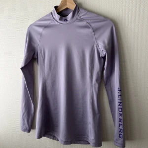 J.Lindeberg - Lila tröja med hög krage från J.Lindeberg i nyskick! Figursydd i storlek S. Nypris 700kr. 