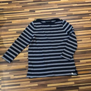 Randig tröja - Tröjan är är helt ny, använd Max 3-5 gånger. Det är en randig marinblå tröja med guldknappar vid kragen. Armarna är lite kortare än hellång. Varan har inga defekter alls.