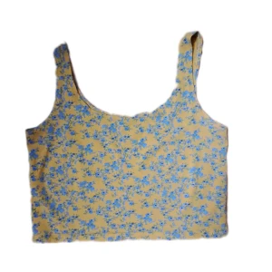 Crop top - Gul crop top/linne med blommor på. Stretchigt och mjukt material, nyskick. Säljer då den inte kommer till användning.