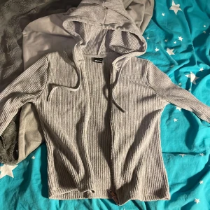 Rib hoddie  - Det är en grå långärmad tröja med en dragkedja som kan öppna åt Boda hållen, se bild. Köpt för 400kr säljs för 320kr. Aldrig använd. 