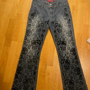 Bootcut - Fantastiska bootcut lågmidjade jeans me sammets blommor på. Dubbelknäppta å i jättefint skick, jag är 165 cm som referens. MÅTT: 36cm midja mätt tvärs över  77cm innerbenslängd 