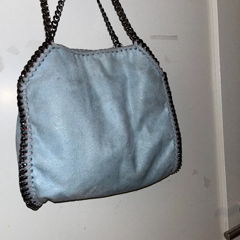 Ljusblå Stella väska. Vattenskadad, fläckig därför sänkt pris. Fläckarna syns inte så tydligt när man är i vanligt ljus.. Väskor.