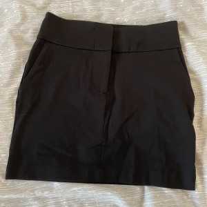 Svart mini skirt  - Helt oanvänd mini skirt från Gina tricot i storlek XS. Säljer då jag aldrig hann lämna tillbaka och den är för liten :( Ganska tajt men finns lite stretch (endast 8% stretchmateriel enligt hemsidan). Resten av materialet är i kostym❤️ Perfekt till fest!🥰